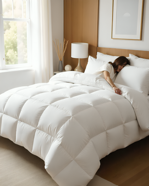 Person sleeping under a white comforter in a bedroom with a lamp and window in the background.