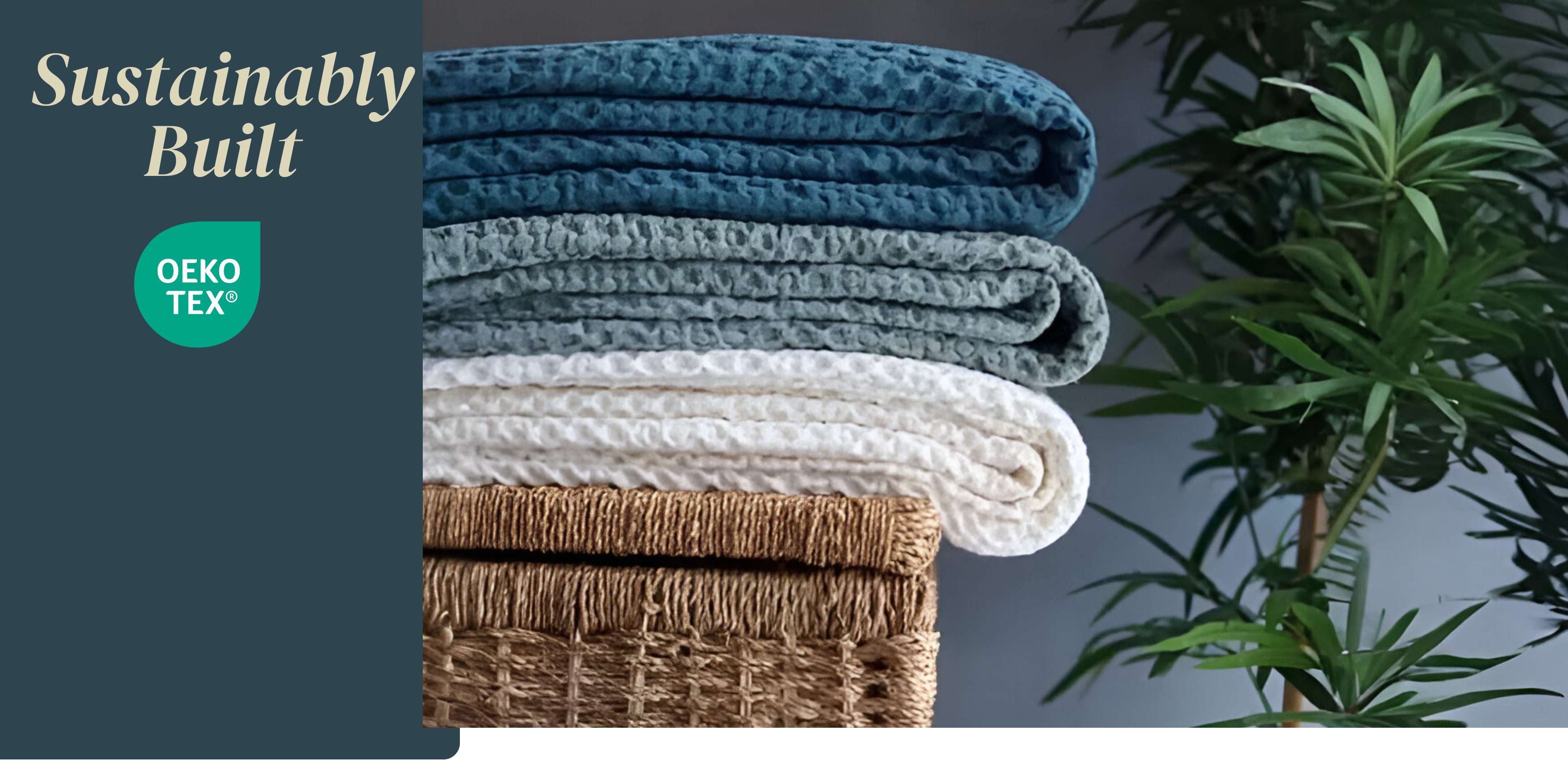 Stack of folded blankets in blue, gray, and white with a wicker basket and plant in the background.